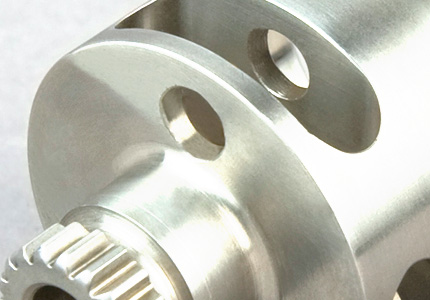 a mechanical component, which appears to be part of a gear system. Notable features include a toothed section that is likely part of a smaller gear or pinion. This interacts with larger gears or racks to transmit rotational force. There are also several holes, probably for mounting or securing this component within a larger assembly. The surface is highly polished, indicating precision engineering, which is typical in industries requiring high reliability and performance, like aerospace or automotive sectors. The quality of machining suggests that this is a component designed for high-stress environments, where precision and durability are crucial.