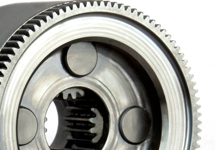 a complex machined metal gear or component. It features internal and external teeth, suggesting it may be part of a gear system or a mechanical coupling. The central part shows intricate details, possibly splines, for a shaft connection. The outer ring has finely machined gear teeth, and the smooth, polished surface indicates a high-quality manufacturing process. The presence of multiple sets of teeth could imply a specific functionality within a larger machine, potentially for power transmission with precise control.