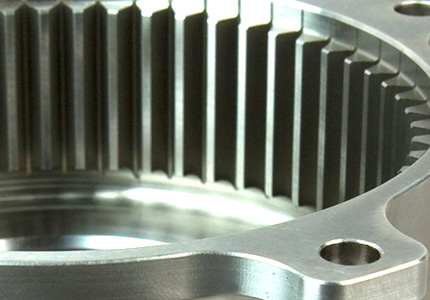 a close-up of a machined gear with fine, straight teeth indicative of precision engineering. The gear's surface is highly finished, suggesting it has been machined to tight tolerances, which is essential for the gear's performance and longevity in its intended mechanical application. You can see the gleaming metal surface reflecting light, which might be a result of a post-machining process like polishing or buffing. There's also a hole drilled into the gear's body, likely for mounting or alignment purposes in an assembly. The image captures the intricate details of the gear's teeth and the subtle variations in the metal's finish, highlighting the meticulousness of modern machining capabilities.